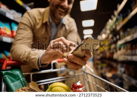 Close up of buyer using app on smart phone in a supermarket. 