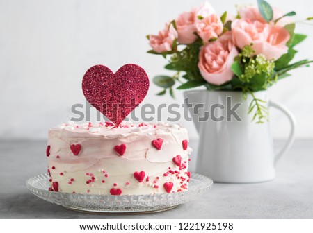 Close Up of a cake decorated with small hearts with heart cake topper, against a gray background. Romantic love concept. Valentine's, Mother's Day, Birthday Cake card Background. Horizonlal.