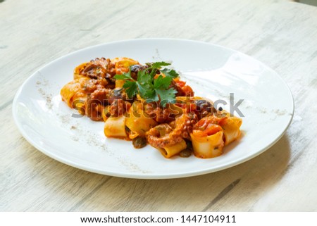 close up of calamarata octopus italian traditional sicilian pasta homemade seafood sauce with tomato,basil,parsley,herbs,chilly prepared by professional chef in a fine dining restaurant