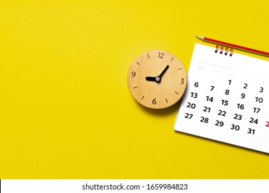 close up of calendar and alarm clock on the yellow table, planning for business meeting or travel planning concept