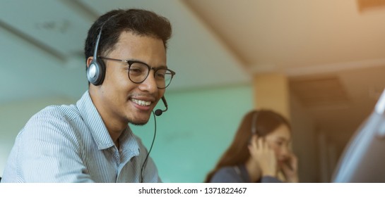 Close Up Call Center Latin Man Wear Headset For Talking With Customer And Working With Asian Employee Colleague Woman At Operation Room , Help Desk Support Concept