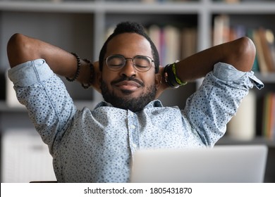 Close up calm African American businessman relaxing daydreaming at workplace, satisfied young man sitting with hands behind head, leaning back in comfortable office chair with closed eyes - Powered by Shutterstock