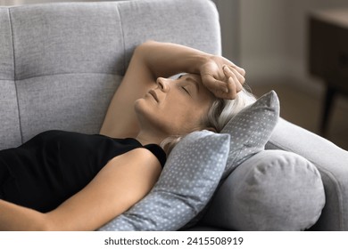 Close up calm mature female felt asleep lying down on couch at home, take break, having healthy daytime nap, restore strength and energy looks peaceful, relieving fatigue after hard working day. Rest - Powered by Shutterstock