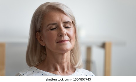 Close Up Calm Peaceful Mature Woman Relaxing With Closed Eyes, Serene Relaxed Older Retired Female Breathing Deep, Meditating, Resting At Home, Enjoying Weekend, Free Time, No Stress Concept