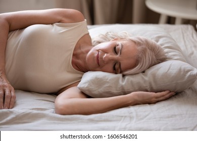 Close up of calm senior woman lying on side sleeping peacefully in comfortable bed soft pillow, tired elderly female or grandmother rest fall asleep taking nap in cozy bedroom, relaxation concept - Powered by Shutterstock