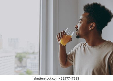 Close up calm young african american man in casual clothes drink orange juice eat breakfast muesli cereals with milk fruit in bowl prepare cooking food in kitchen at home indoor. Healthy diet concept. - Powered by Shutterstock