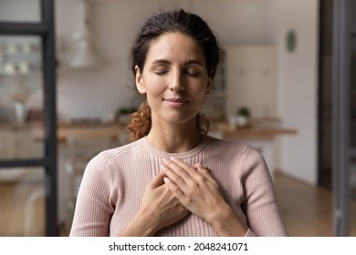 Close up of calm young Caucasian woman hold hands on heart chest feel grateful and thankful. Happy millennial female show gratitude, love and care, pray or visualize. Religion, faith concept. - Shutterstock ID 2048241071