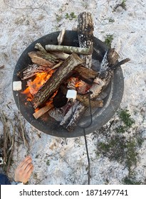 Close Up Of A Camp Site Fire Roasting Marshmallows Over It To Create Smores As A Snack. 