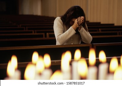 Close up of candles lit with woman praying in church Foto Stock