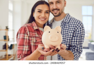 Close up captures a couple hands jointly hold a piggy bank at home. Family smiles radiate joy and togetherness, reflecting shared commitment to saving money for future. - Powered by Shutterstock