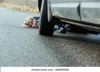 Close Up of Car Accident Fatality - Young Teenage Boy Has Been Hit by a Car and is Lying Unconscious on Road Pavement with Various Injuries, Car Visible in Foreground - Powered by Shutterstock