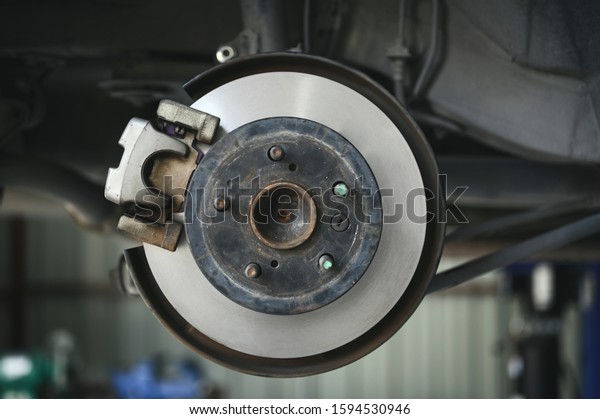 Close up of car brake repairing in garage ,disc\
brake of the vehicle for\
repair.