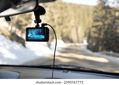 Close up of car camera mount on the windshield. Dash camera records the view through a vehicle's front windscreen. Video evidence in event of a road incident