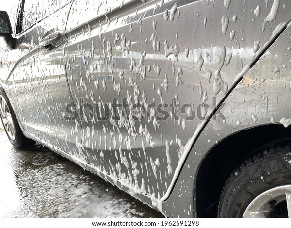 Close up of a car covered partially with\
cleaning foam during a car washing\
exercise