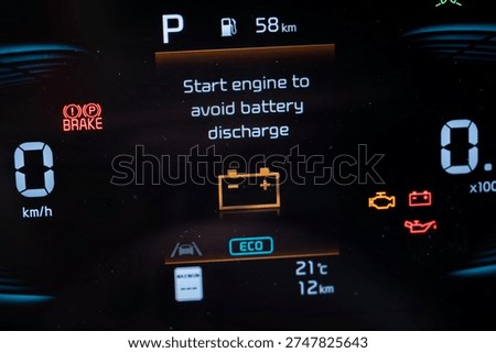 Close up of car dashboard warning message about battery discharge.