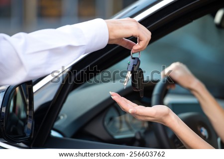 Close up of car dealer giving keys of a new car to woman. Concept for car rental 