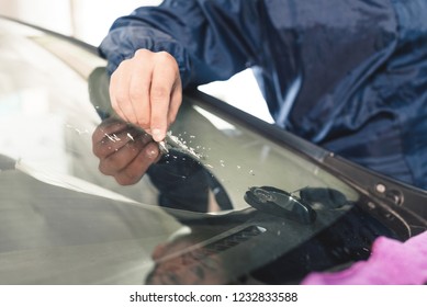 Close up Car glaze worker fixing and repairing a windshield or windshield of a car at a garage service station. Drill glass for repair - Powered by Shutterstock