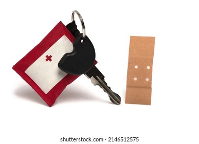 Close up of car key with small red pocket with a tiny red cross on key fob for storing first aid plaster on white background