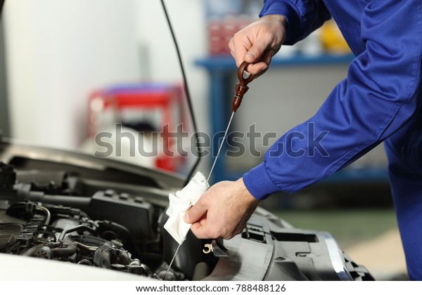 Close up of a car mechanic checking oil level in\
a mechanical workshop