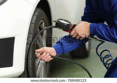 Close up of a car mechanic hands checking tire air with a pressure gauge