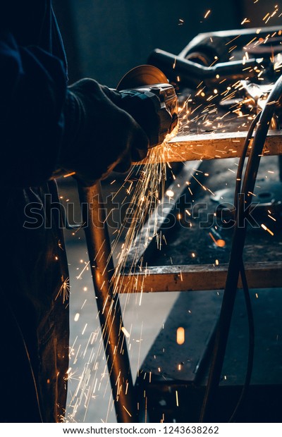 Close up\
of car mechanic hands welding grinding machine.Sparks of grinding\
machine while cutting car exhaust\
pipe