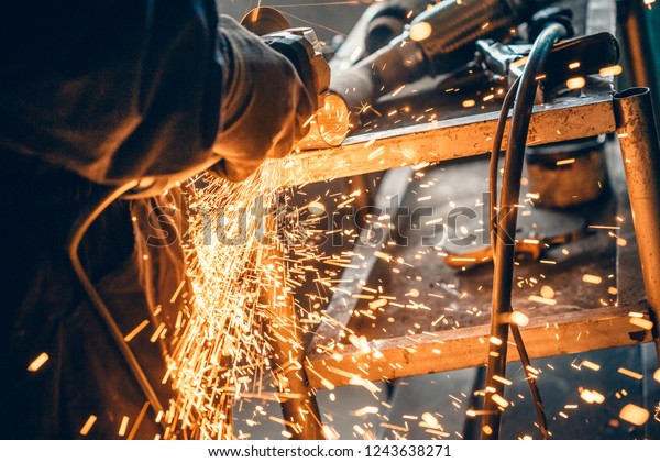 Close up\
of car mechanic hands welding grinding machine.Sparks of grinding\
machine while cutting car exhaust\
pipe