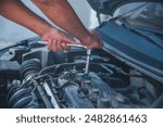 Close up Car Mechanic man hands repairing car auto repair shop. Man hands fixing machinery vehicle mechanical service. open vehicle hood checking up auto mobile. Vehicle Car maintenance engineer.