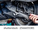 Close up car mechanic with tool checking underneath vehicle in auto repair service, car maintenance concept