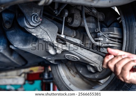 Close up car mechanic with tool checking underneath vehicle in auto repair service, car maintenance concept