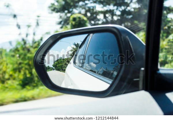 Close\
up of car mirror with reflection of behind the\
car.