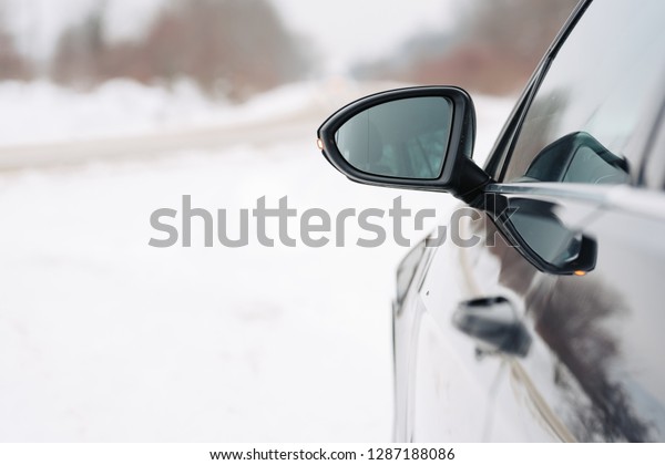 Close\
up of car mirror with reflection of behind the\
car.