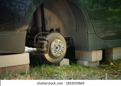 Close Up Of Car On Bricks Outside. Concept Of Stolen Vehicle Wheels. Car With Missing Wheel.