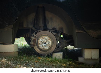 Close Up Of Car On Bricks Outside. Concept Of Stolen Vehicle Wheels. Car With Missing Wheel.