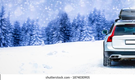 Close Up Car On Snowy Road With Trunk Box Fixed On Rooftop. Winter Family Holiday Trip To Ski Resort.  Snowy Blur Trees In Background.