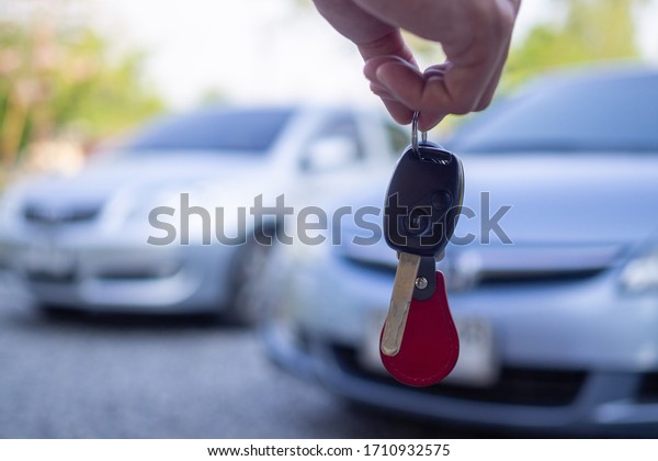 Close up of the car owner\'s hand holding the\
delivery key to buyers. Concept of selling cars and giving keys to\
new owners.