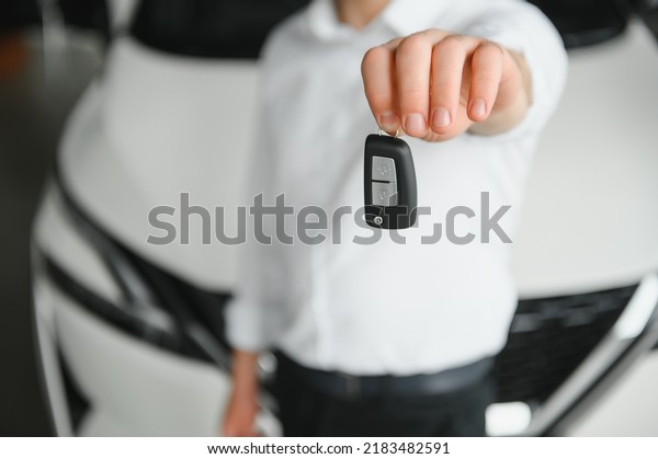 Close up of the car owner\'s hand holding the\
delivery key to buyers. Concept of selling cars and giving keys to\
new owners.