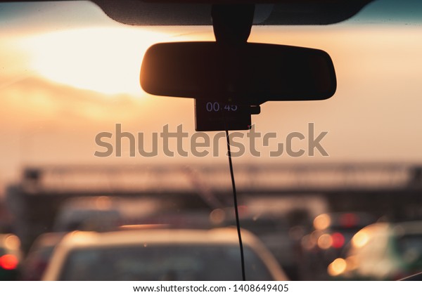 Close up of Car rear view mirror during sunset golden\
hour during the summer on the expressway with a lot of car and\
traffic jam