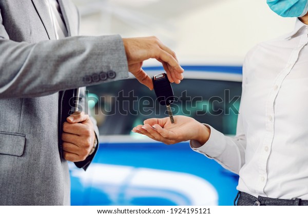 Close up\
of car seller handing car keys to a\
customer.