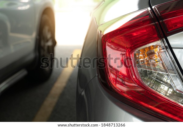 Close up of car tail\
lamp gray color parking on asphalt road. with blurred other car and\
yellow line.