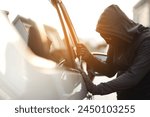 Close up car thief hand holding screwdriver tamper yank and glove black stealing automobile trying door handle to see if vehicle is unlocked trying to break into inside.	