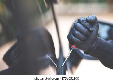 Close Up Car Thief Hand Holding Screwdriver Tamper Yank And Glove Black Stealing Automobile Trying Into Glass Door Window Edge To See If Vehicle Is Unlocked  Trying To Break Inside. 