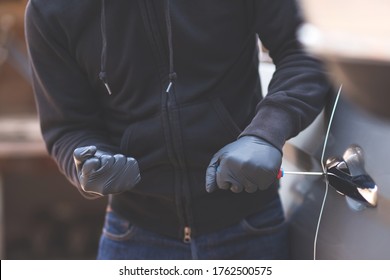 Close Up Car Thief Hand Holding Screwdriver Tamper Yank And Glove Black Stealing Automobile Trying Door Handle To See If Vehicle Is Unlocked  Trying To Break Into Inside. 