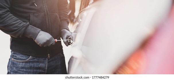 Close Up Car Thief Hand Holding Screwdriver Tamper Yank And Glove Black Stealing Automobile Trying Door Handle To See If Vehicle Is Unlocked  Trying To Break Into Inside. 