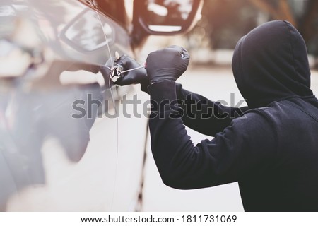 Close up car thief hand holding screwdriver tamper yank and glove black stealing automobile trying door handle to see if vehicle is unlocked  trying to break into inside. 