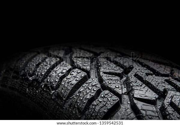 Close up of car tire  with water droplets\
isolated on black\
background