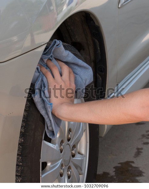  Close up  Car wash . Hand of worker car washing\
alloy wheels on a car wash