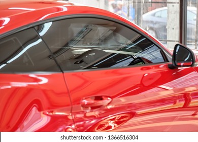 Close Up Of Car Window Tint. Ceramic Film Provide Heat Rejection & UV Protection With Color Stable Shade. Automobile Film Installed To Glass Surface Of Red Car. Professional Tinting Service Background