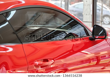 Close up of car window tint. Ceramic film provide heat rejection & UV protection with color stable shade. Automobile film installed to glass surface of red car. Professional tinting service background