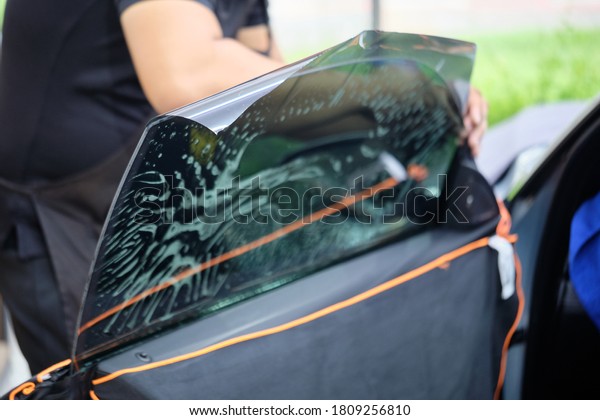 Close up of car window tint. Ceramic film provide\
heat rejection & UV protection with color shade. Automotive\
film installed to car glass surface. Professional tinting service\
background. Shallow DOF.