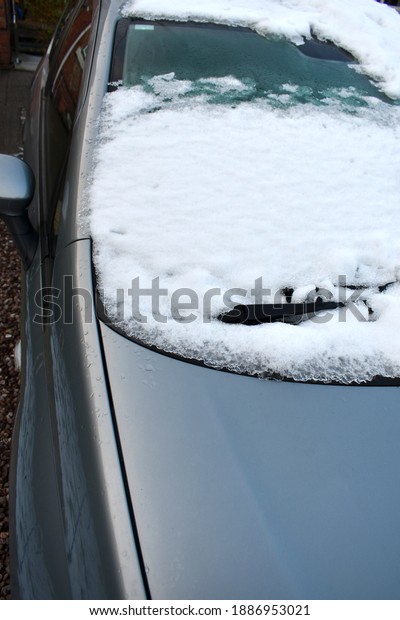close up of car windscreen and wiper blade covered\
in deep white snow in\
winter